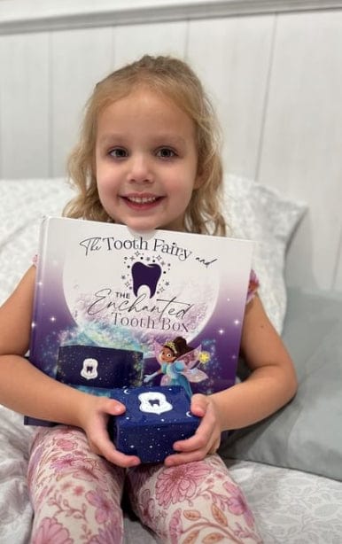 Happy girl holding book and tooth fairy box